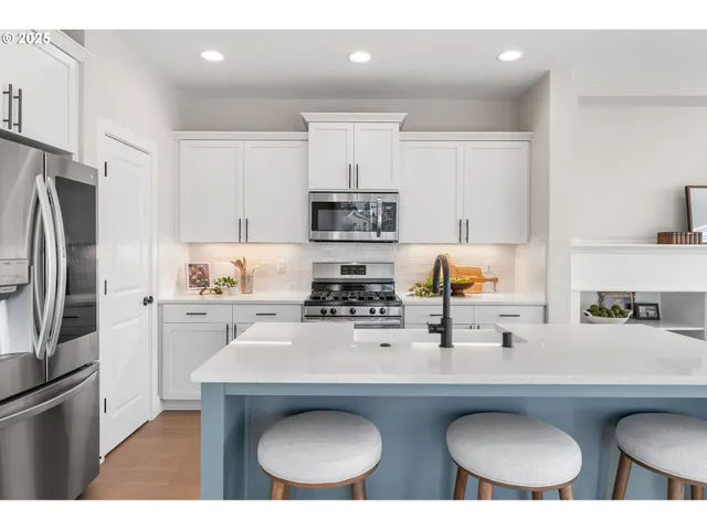 a kitchen with stainless steel appliances a sink a stove a refrigerator and cabinets
