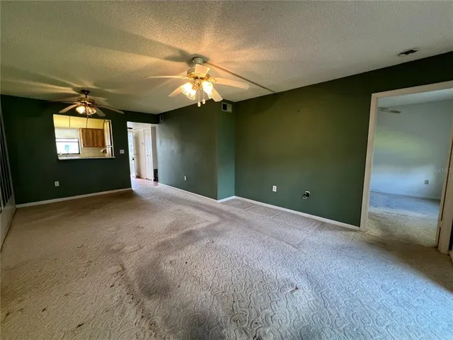 an empty room with windows and fan