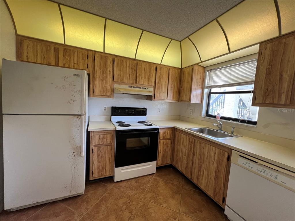 4186 27th Court Southwest, Unit 105 Naples, FL 34116 - Photo 4 of 14 a kitchen with stainless steel appliances granite countertop a refrigerator a stove and a sink