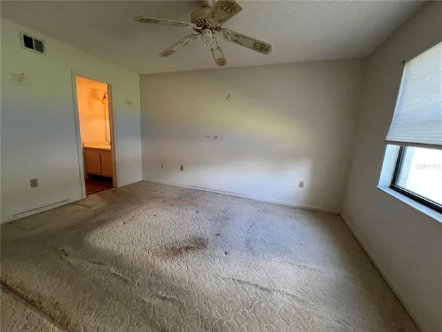 an empty room with windows and chandelier fan