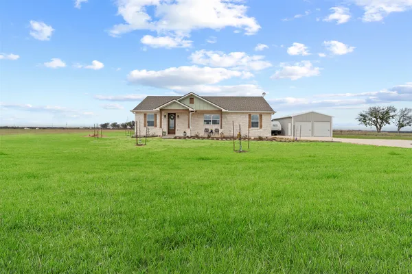 a view of a house with a big yard and large trees