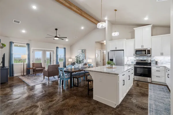 a kitchen with stainless steel appliances kitchen island granite countertop a table chairs and a refrigerator