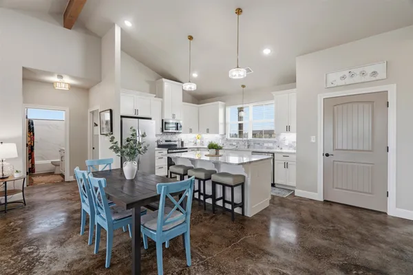 a kitchen with a dining table chairs wooden floor and appliances