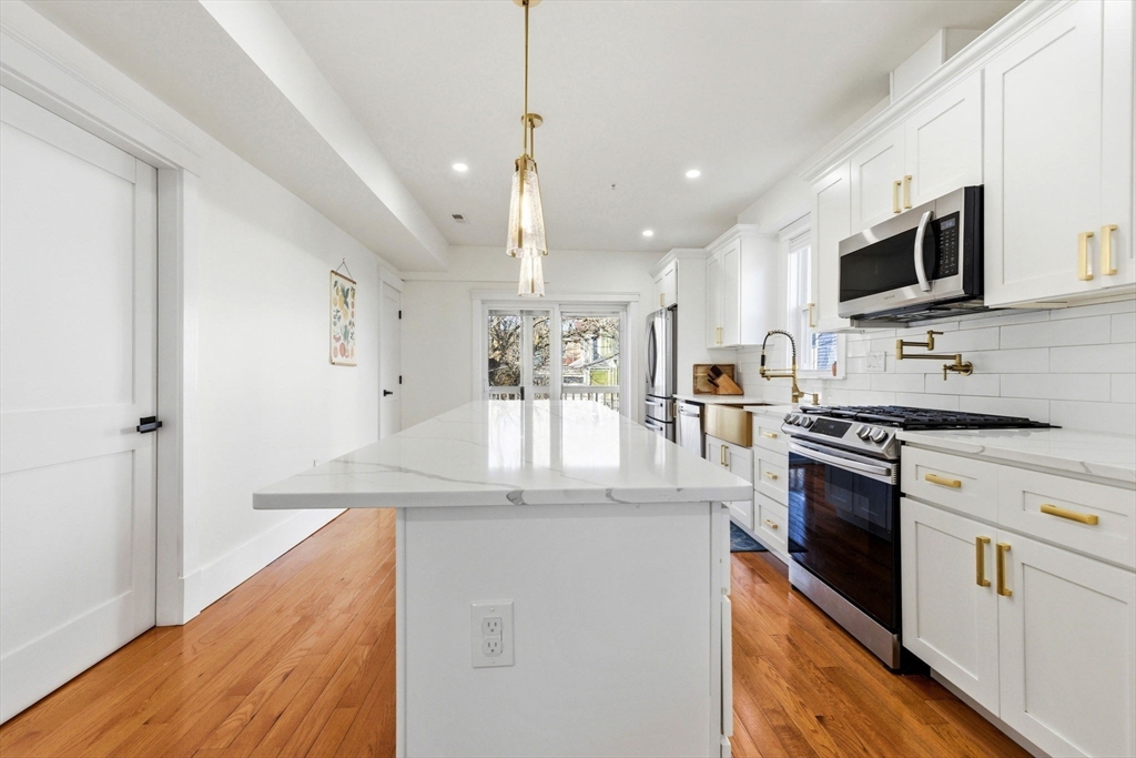 567 Park Street, Unit 2 Boston, MA 02124 - Photo 1 of 20 a kitchen with stainless steel appliances granite countertop a refrigerator a stove microwave and white cabinets with wooden floor