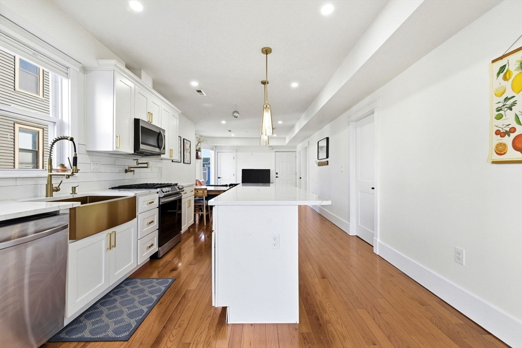 567 Park Street, Unit 2 Boston, MA 02124 - Photo 4 of 20 a large kitchen with stainless steel appliances granite countertop a white stove top oven a sink dishwasher and a refrigerator with wooden floor