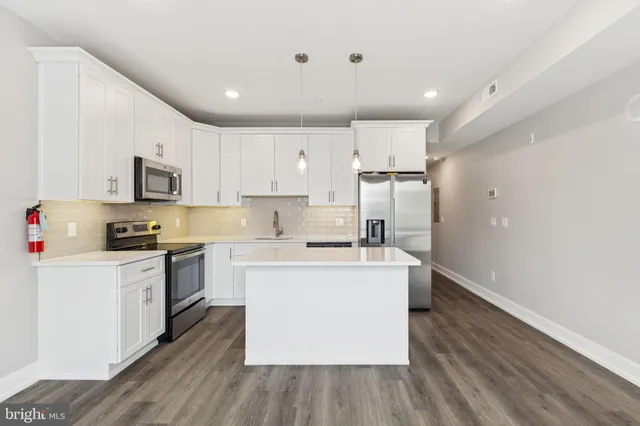 a kitchen with stainless steel appliances granite countertop a stove top oven a refrigerator a sink and dishwasher with wooden floor