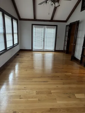 a view of an empty room with wooden floor and a window