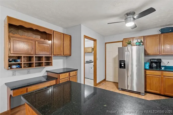 a kitchen with stainless steel appliances granite countertop a refrigerator a stove and a sink with wooden floor
