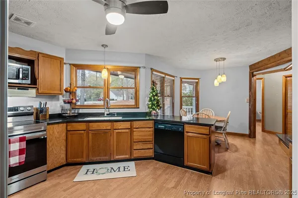 a kitchen with stainless steel appliances granite countertop a sink dishwasher stove and wooden cabinets