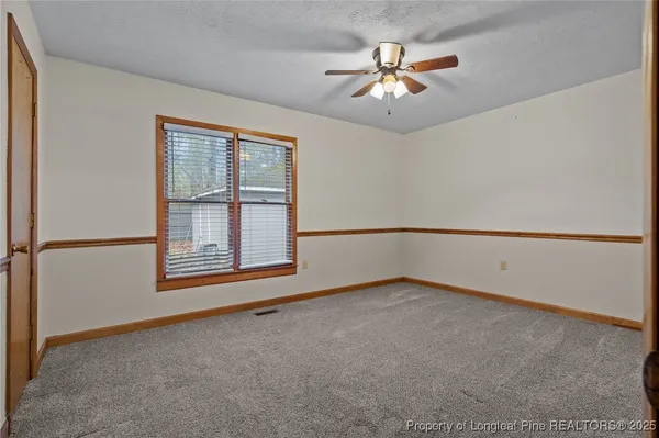 an empty room with chandelier fan and windows