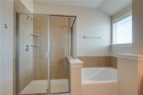 4679 Edith Street Plano, TX 75024 - Photo 25 of 34 Glass-enclosed shower with tile surround and built-in shelving, accompanied by a separate soaking tub