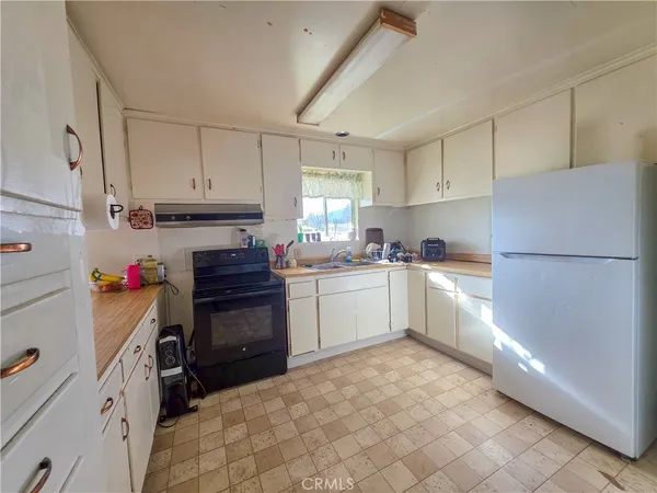 a kitchen with a refrigerator and white cabinets