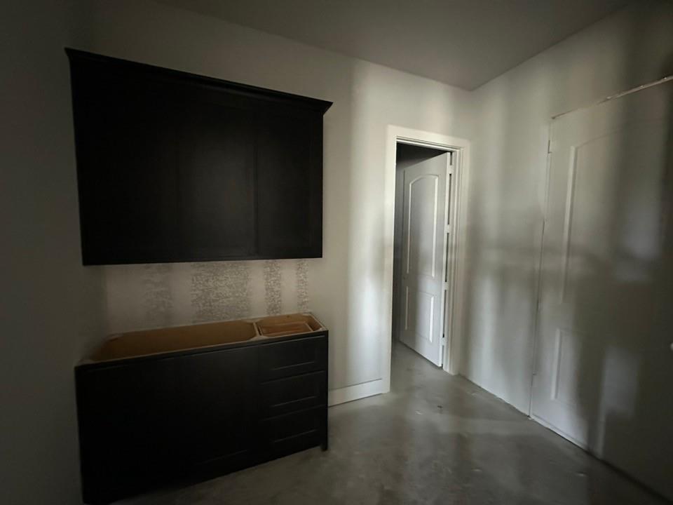 295 Brown Road Leonard, TX 75452 - Photo 15 of 26 Unfinished space featuring a dark wood-finish vanity base, a coordinating dark wood-finish wall-mounted cabinet, and light-toned patterned wallpaper
