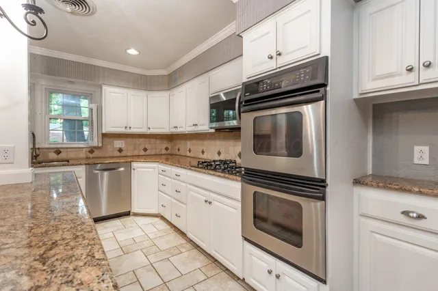 a kitchen with granite countertop cabinets stainless steel appliances and a counter space