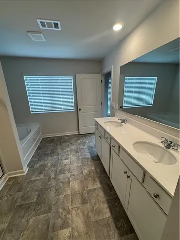 a spacious bathroom with a granite countertop sink a large mirror and a bathtub