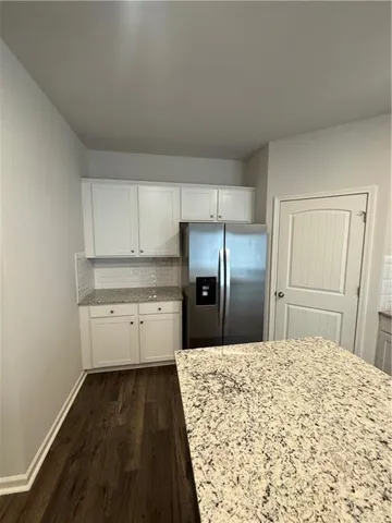 a kitchen with granite countertop a refrigerator sink and cabinets