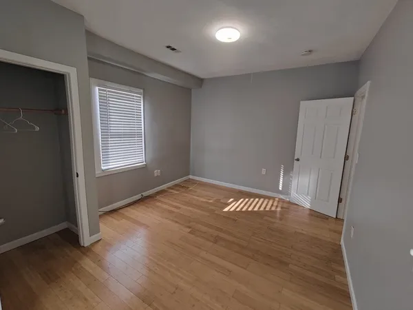 an empty room with wooden floor and windows