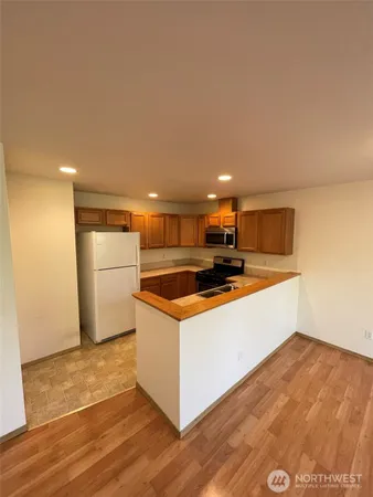 a view of kitchen with stainless steel appliances wooden floor and large window