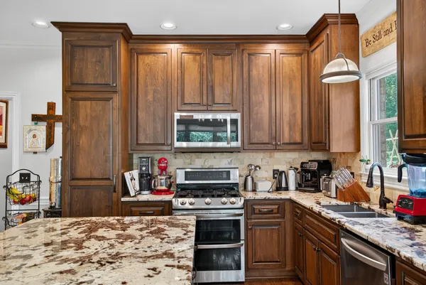 a kitchen with stainless steel appliances granite countertop a stove a sink and a microwave