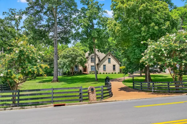 a view of a house with a big yard and large trees