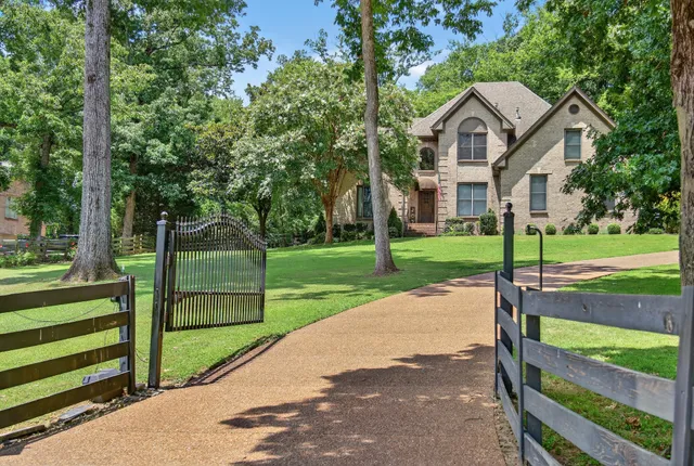 a view of a house with a big yard and large trees
