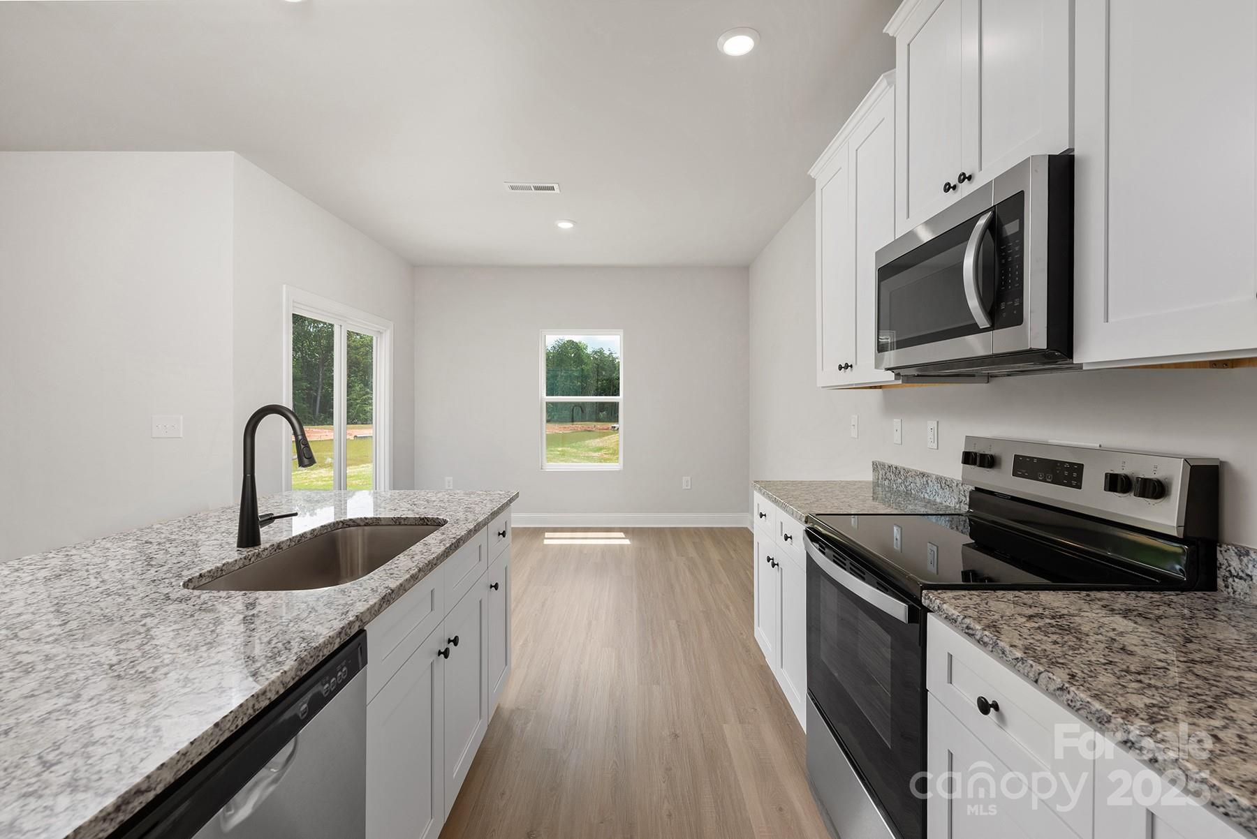 7117 Jerimoth Drive Charlotte, NC 28215 - Photo 7 of 12 a kitchen with granite countertop a sink a stove top oven a counter space and cabinets