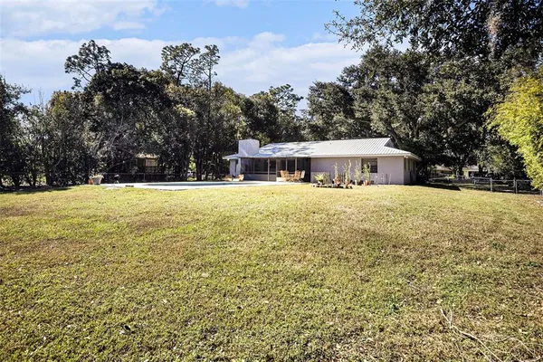 a view of house with swimming pool and trees in the background