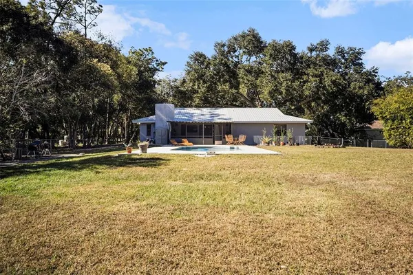 a view of house with swimming pool and trees in the background