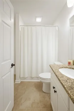 a bathroom with a granite countertop sink and a toilet