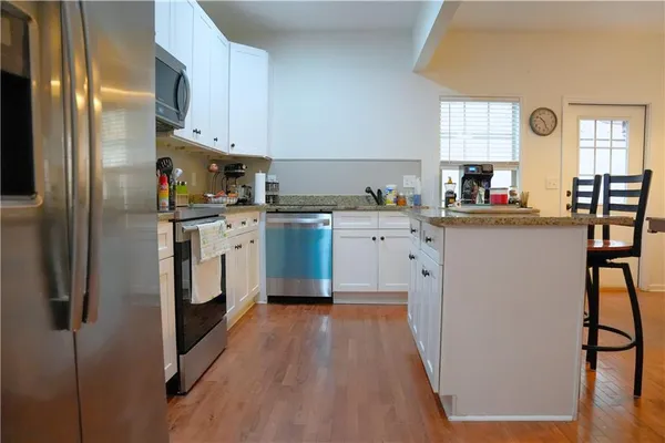 a kitchen with stainless steel appliances granite countertop a stove top oven a sink and a refrigerator