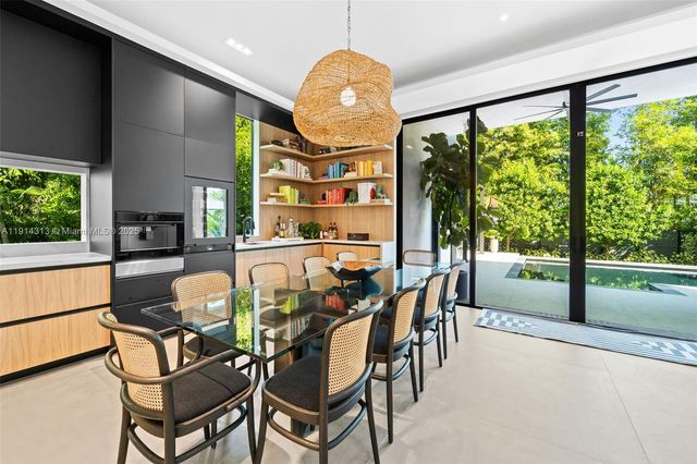 a dining room with furniture a chandelier and a floor to ceiling window