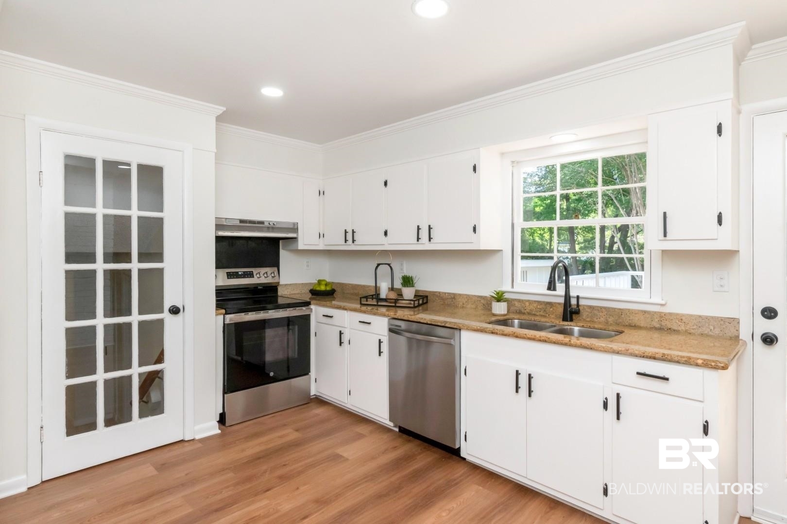 115 Pineridge Road Daphne, AL 36526 - Photo 12 of 34 Kitchen featuring white cabinets, under cabinet range hood, a sink, light wood-style floors, and appliances with stainless steel finishes
