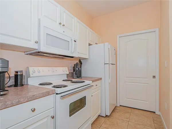 a kitchen with granite countertop white cabinets and refrigerator
