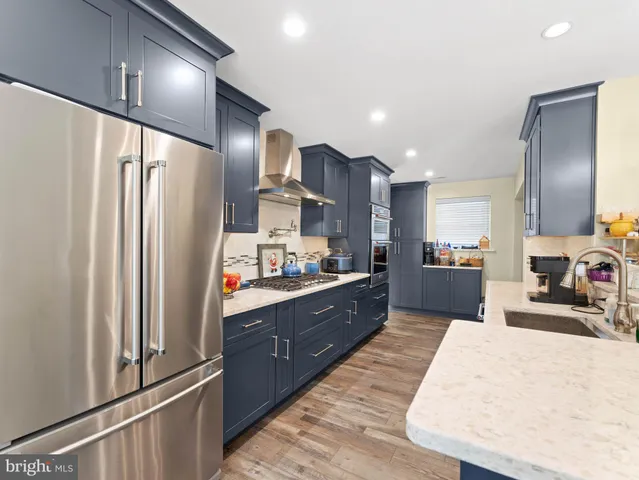 a large kitchen with stainless steel appliances kitchen island a large counter top and a refrigerator