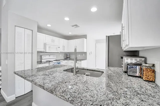 a kitchen with stainless steel appliances granite countertop a sink refrigerator and cabinets