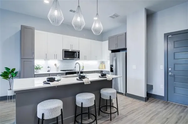 a kitchen with a dining table chairs stainless steel appliances and cabinets