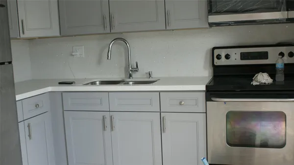 a kitchen with white cabinets and sink