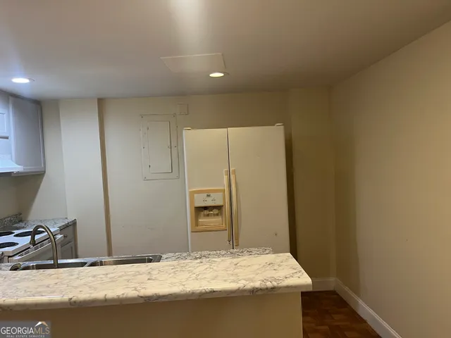 a bathroom with a granite countertop sink and a refrigerator