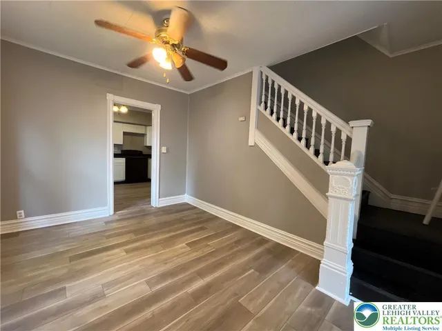 a view of an empty room with a window and wooden floor