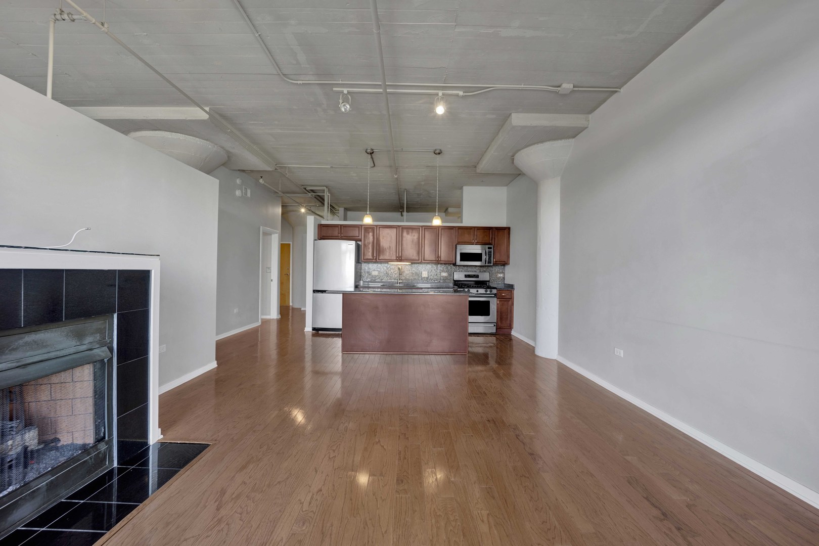 1525 South Sangamon Street, Unit 504 Chicago, IL 60608 - Photo 12 of 32 a view of kitchen and an empty room with wooden floor