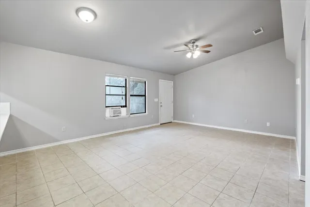 an empty room with windows and ceiling fan