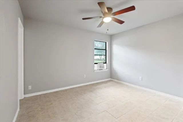 an empty room with windows and ceiling fan