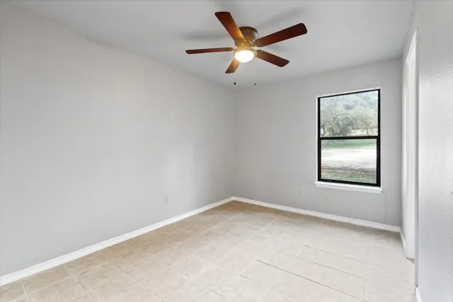 an empty room with a window and a ceiling fan