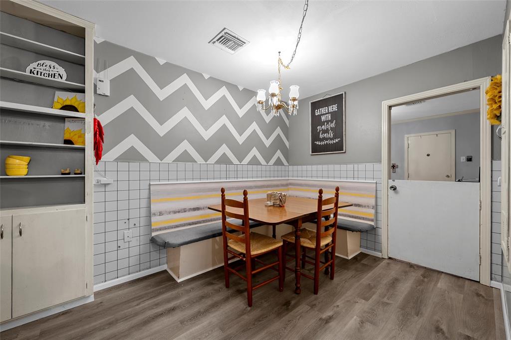 301 North 40th Street Waco, TX 76710 - Photo 9 of 26 Built-in breakfast nook with upholstered bench seating, wood-finish flooring, white tile wainscoting, and an overhead chandelier