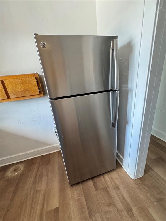 35 North 6th Street, Unit 8 Haines City, FL 33844 - Photo 11 of 17 a view of a refrigerator in kitchen and an empty room with wooden floor