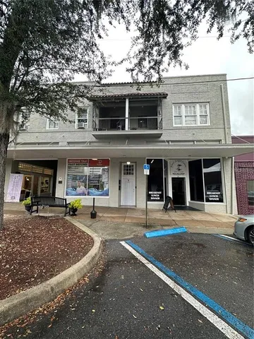 a front view of a building with lots of trees and empty space