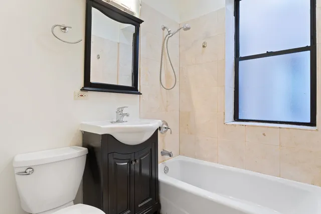 a bathroom with a sink vanity mirror bathtub shower and toilet