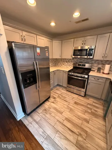 a kitchen with stainless steel appliances granite countertop a refrigerator a stove and a sink