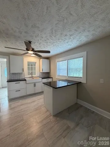 a large kitchen with kitchen island white cabinets and stainless steel appliances