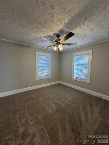 an empty room with windows and fan
